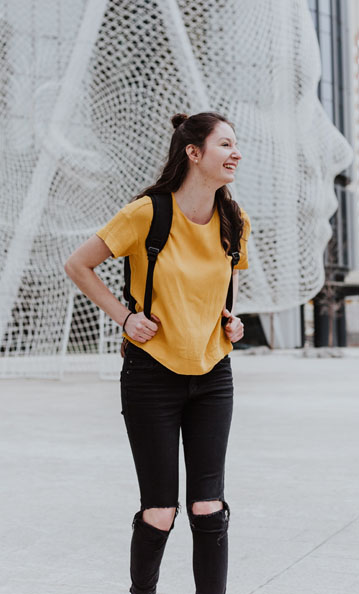 Woman standing smiling with a backpack on
