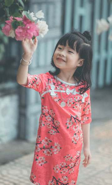 Little girl smiling and touching flowers